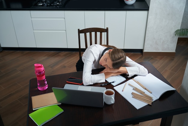 Mujer cansada durmiendo en la mesa después de un largo día de trabajo