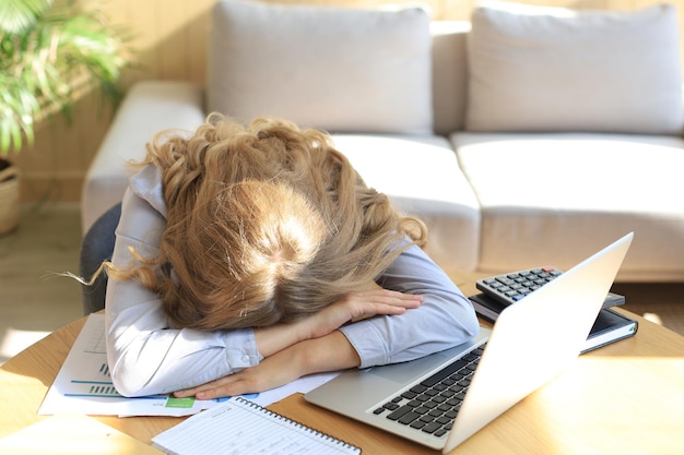 Mujer cansada con exceso de trabajo descansando mientras trabajaba en la computadora portátil.