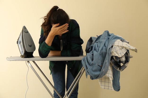 Mujer cansada inclinada sobre una tabla de planchar