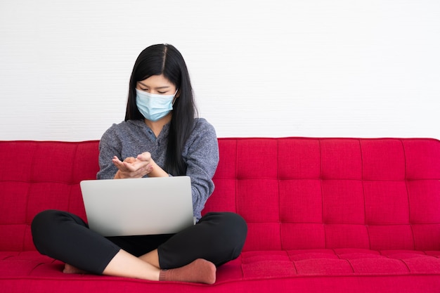 Mujer cansada con una mascarilla, músculos tensos de dolor en la muñeca, el sufrimiento del síndrome de oficina después de largas horas de trabajo en la computadora. Síndrome de oficina y concepto de atención médica.