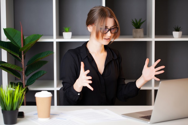 Mujer cansada que trabaja en la computadora en la oficina