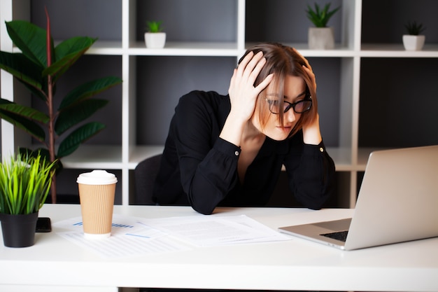 Mujer cansada que trabaja en la computadora en la oficina