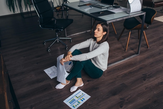 Mujer cansada sentada en el suelo cansada del trabajo