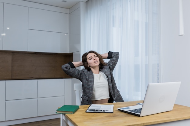 Mujer cansada y soñolienta que trabaja en una computadora portátil, en casa u oficina, trabajando en línea
