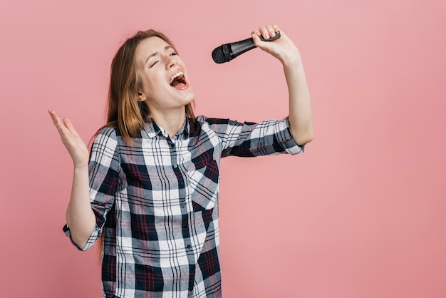 Foto mujer cantando en el micrófono con espacio de copia