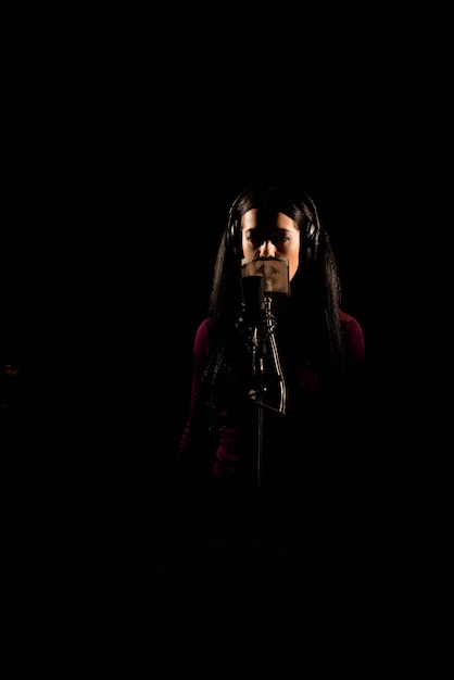 Mujer cantante cantando una canción en el estudio de grabación.