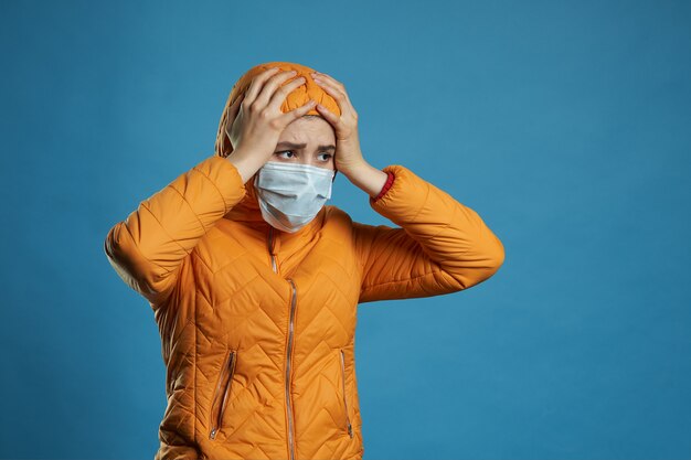 Mujer con capucha en una mascarilla protectora y abrigo