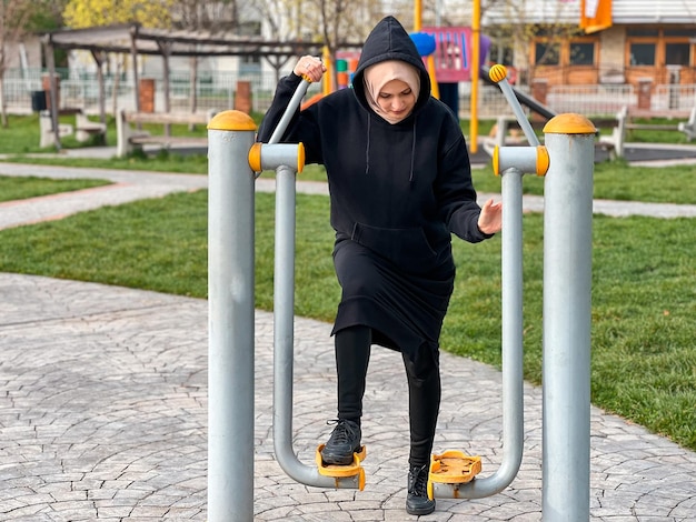 Una mujer con una capucha negra está haciendo ejercicio en un parque.