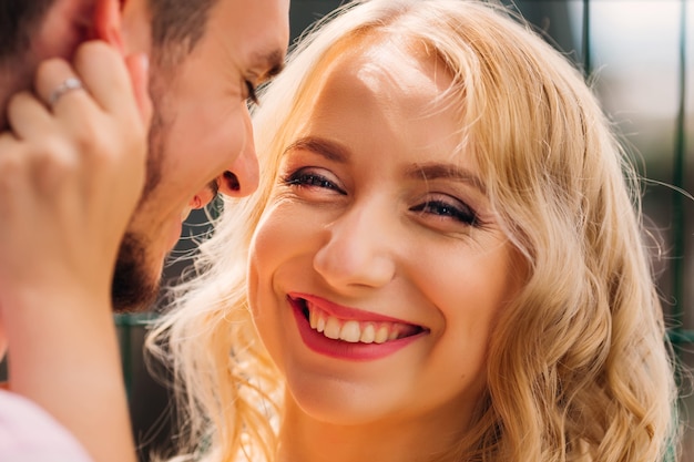 Una mujer con una cara bonita sonríe genuinamente en la lente de la cámara y el chico a su lado