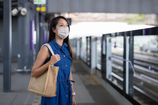 Mujer con cara y espera el tren.