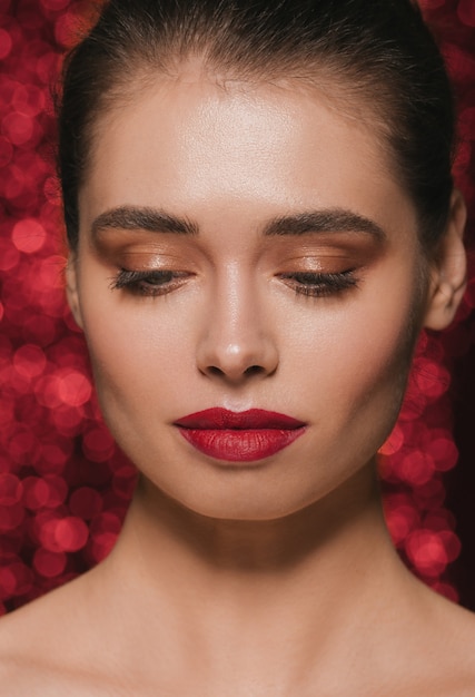 Mujer cara fiesta belleza lápiz labial rojo piel limpia hermoso glamour femenino. Fondo de lentejuelas rojas