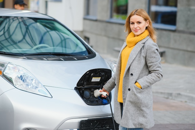 Mujer carga electro coche en la gasolinera eléctrica