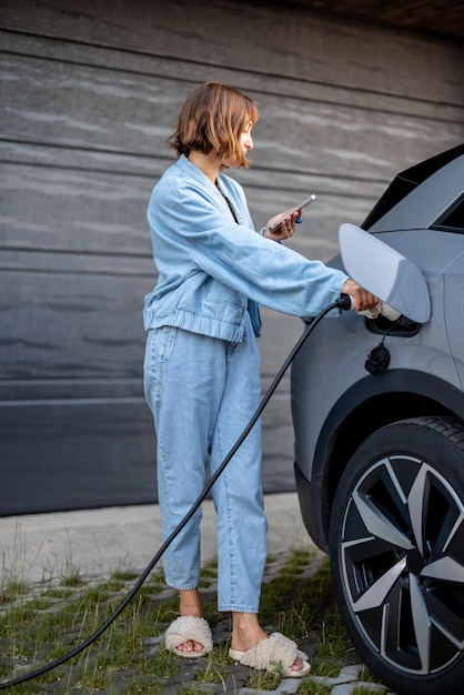 Una mujer carga su coche eléctrico cerca de una casa