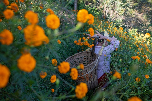 Una mujer cargando una canasta con flores.