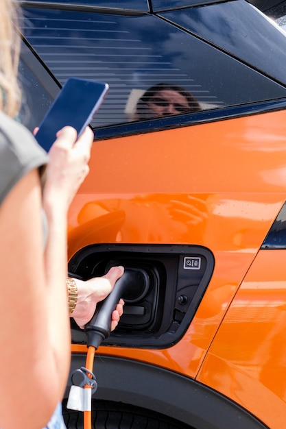 Mujer cargando el coche eléctrico y comprobando su nivel de carga