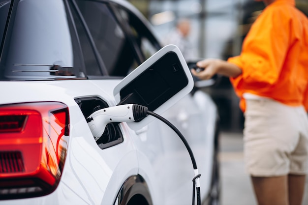 Mujer cargando coche eléctrico en la estación de carga