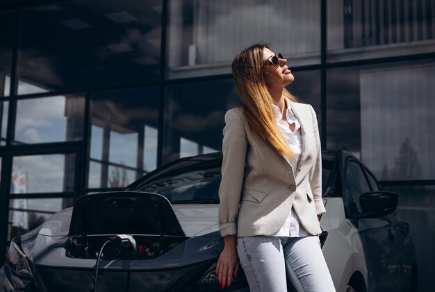 Mujer cargando un coche eléctrico en una estación de carga