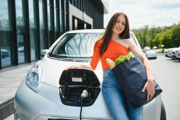 Mujer cargando electro coche en la gasolinera eléctrica