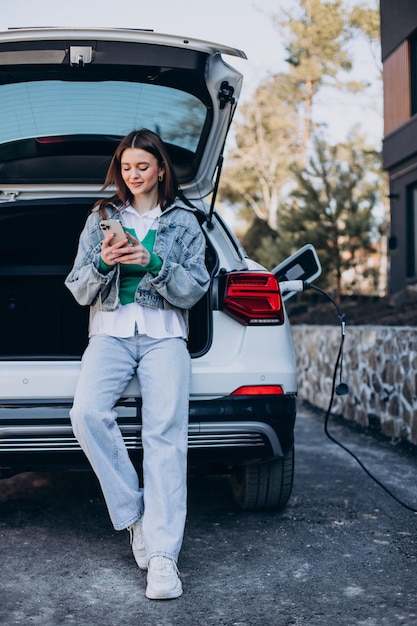 Mujer cargando su auto eléctrico con pistola de carga