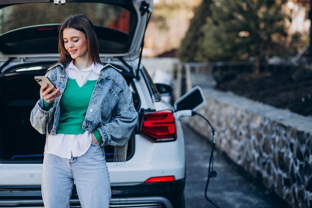 Mujer cargando su auto eléctrico con pistola de carga