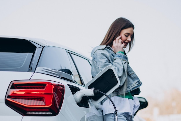 Mujer cargando su auto eléctrico con pistola de carga