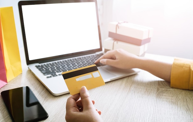 Mujer y carrito de compras pequeño con computadora portátil para el concepto de compras en línea por Internet