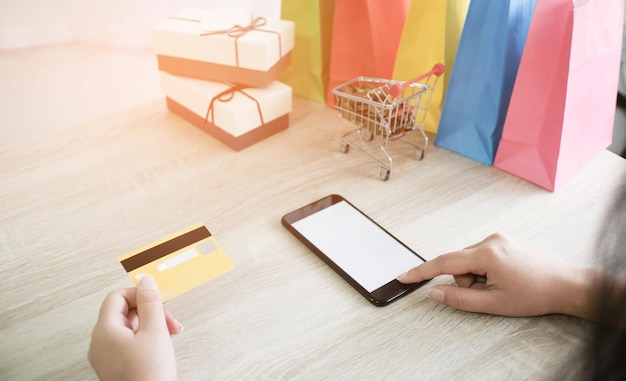 Mujer y carrito de compras pequeño con computadora portátil para el concepto de compras en línea por Internet