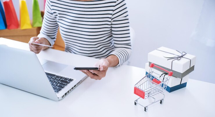 Foto mujer y carrito de compras pequeño con computadora portátil para el concepto de compras en línea por internet