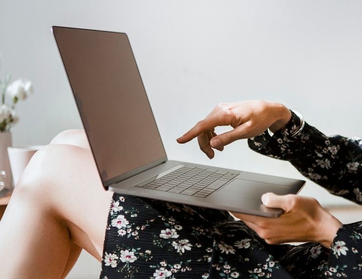 Foto mujer en casa apuntando a la pantalla de un portátil