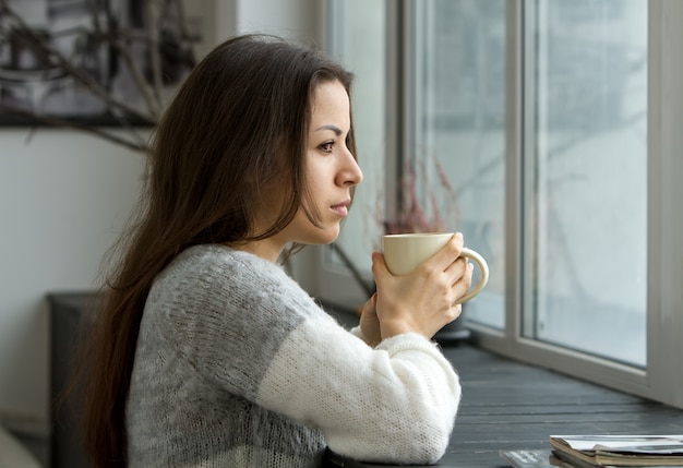 Mujer en la casa bebiendo una taza de café