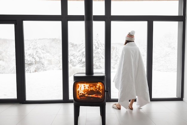 Mujer en casa con chimenea durante el invierno en la naturaleza