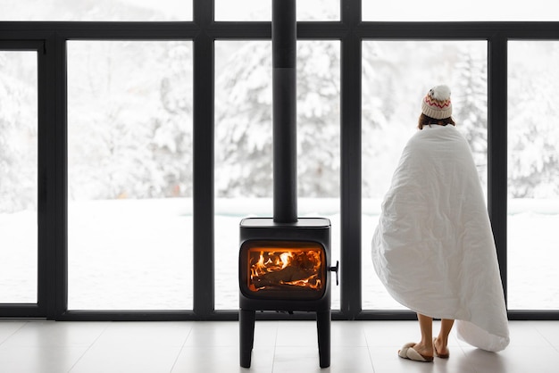 Mujer en casa con chimenea durante el invierno en la naturaleza