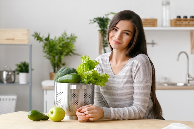 Mujer en casa cocina con verduras para cocinar. Helthy comida casera dieta vitaminas mujer joven y hermosa. Tiro del estudio.