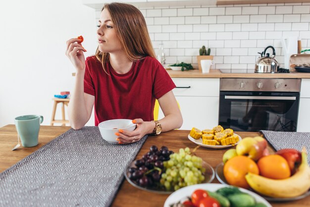 Mujer en casa comiendo frutas y verduras vista superior.