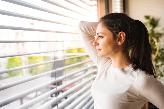 Mujer en casa mirando por la ventana