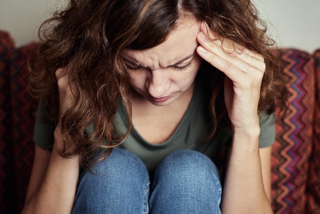 Mujer en casa sintiendo fuerte dolor de cabeza, tocándose las sienes, migraña debido al estrés y agotamiento mental