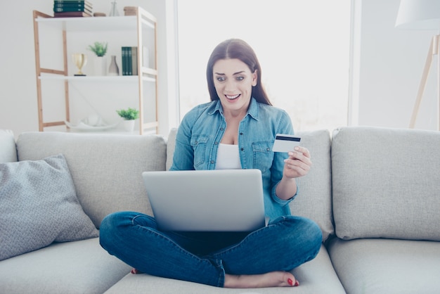 Mujer en casa en el sofá usando la computadora portátil para compras en línea