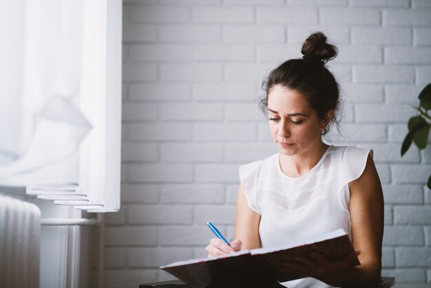 Mujer en casa sosteniendo negocios de trabajo portátil desde casa.