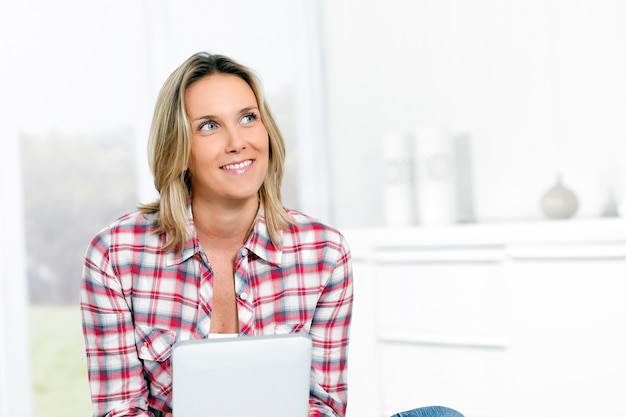 Mujer en casa con tableta mirando a alguien