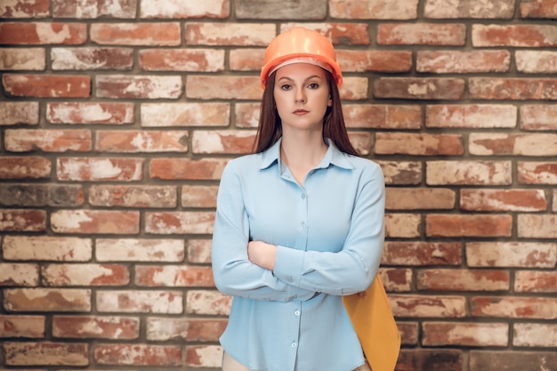 Mujer en casco protector con los brazos cruzados.