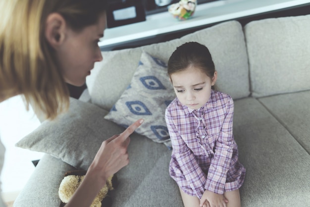 Una mujer castiga a una niña y hace una mueca con el dedo.