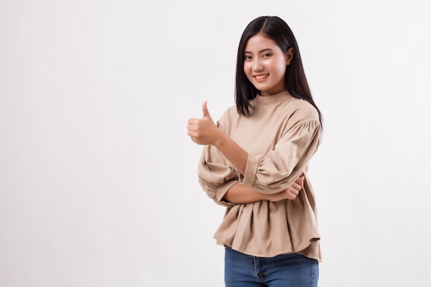 Mujer casual apuntando con el pulgar hacia arriba al espacio en blanco, estudio de modelo de mujer árabe asiática