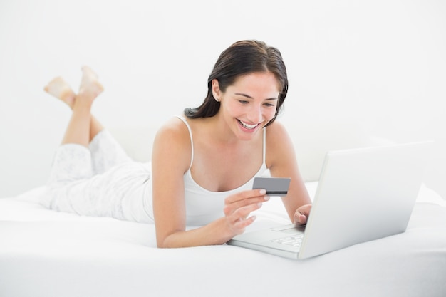 Mujer casual haciendo compras en línea en la cama