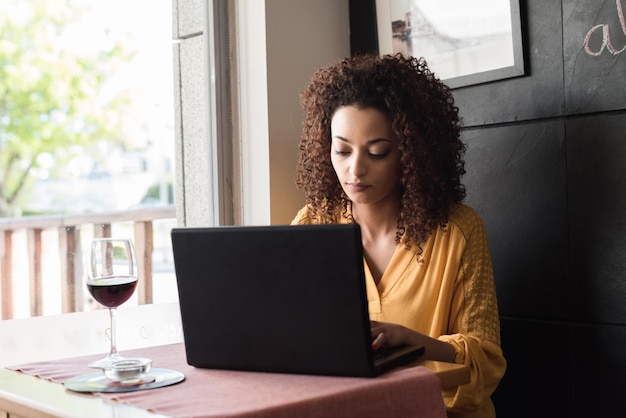 Mujer casual que usa la computadora portátil en la cafetería