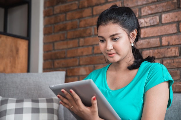 Mujer casual que usa la tableta en casa