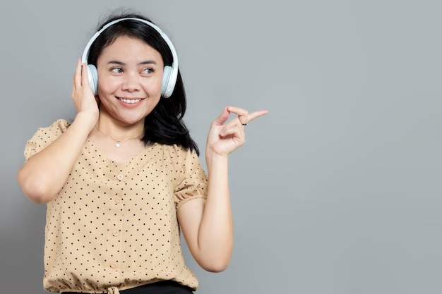 Mujer casual usando audífonos apuntando hacia la derecha