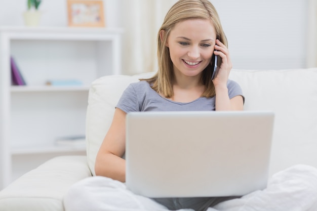 Mujer casual usando la computadora portátil y teléfono celular en casa