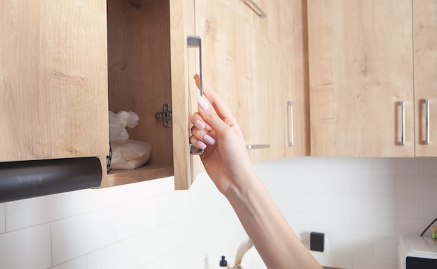 Mujer caucásica abre los muebles de la puerta de la cocina