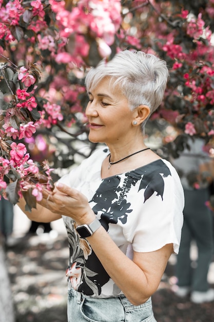 mujer caucásica adulta envejecida en un jardín floreciente