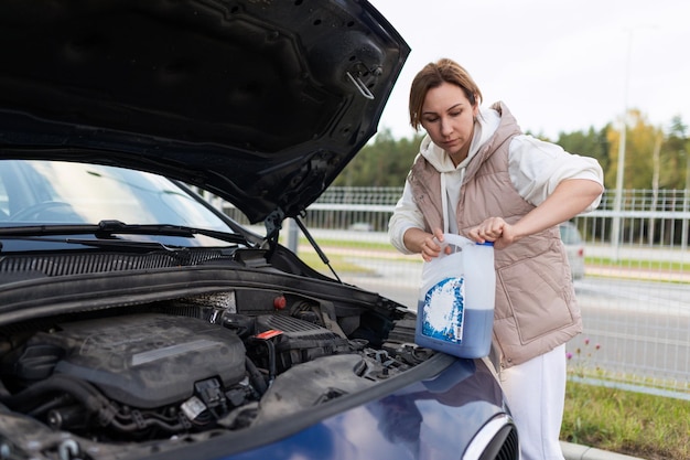 Mujer caucásica adulta vierte refrigerante en el coche